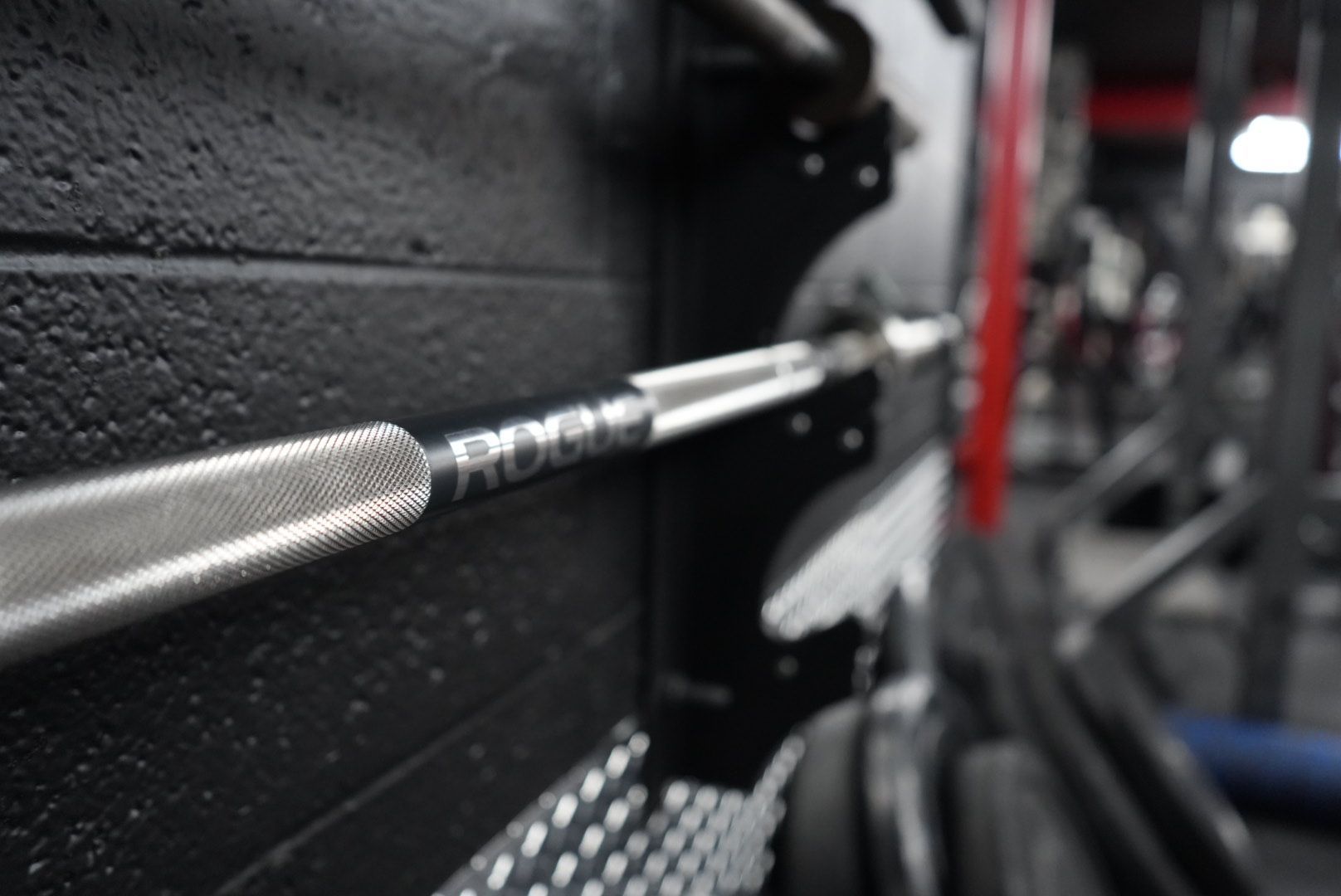 Close-up of a gym cable attachment with knurled handle on black equipment, blurred weight rack in background
