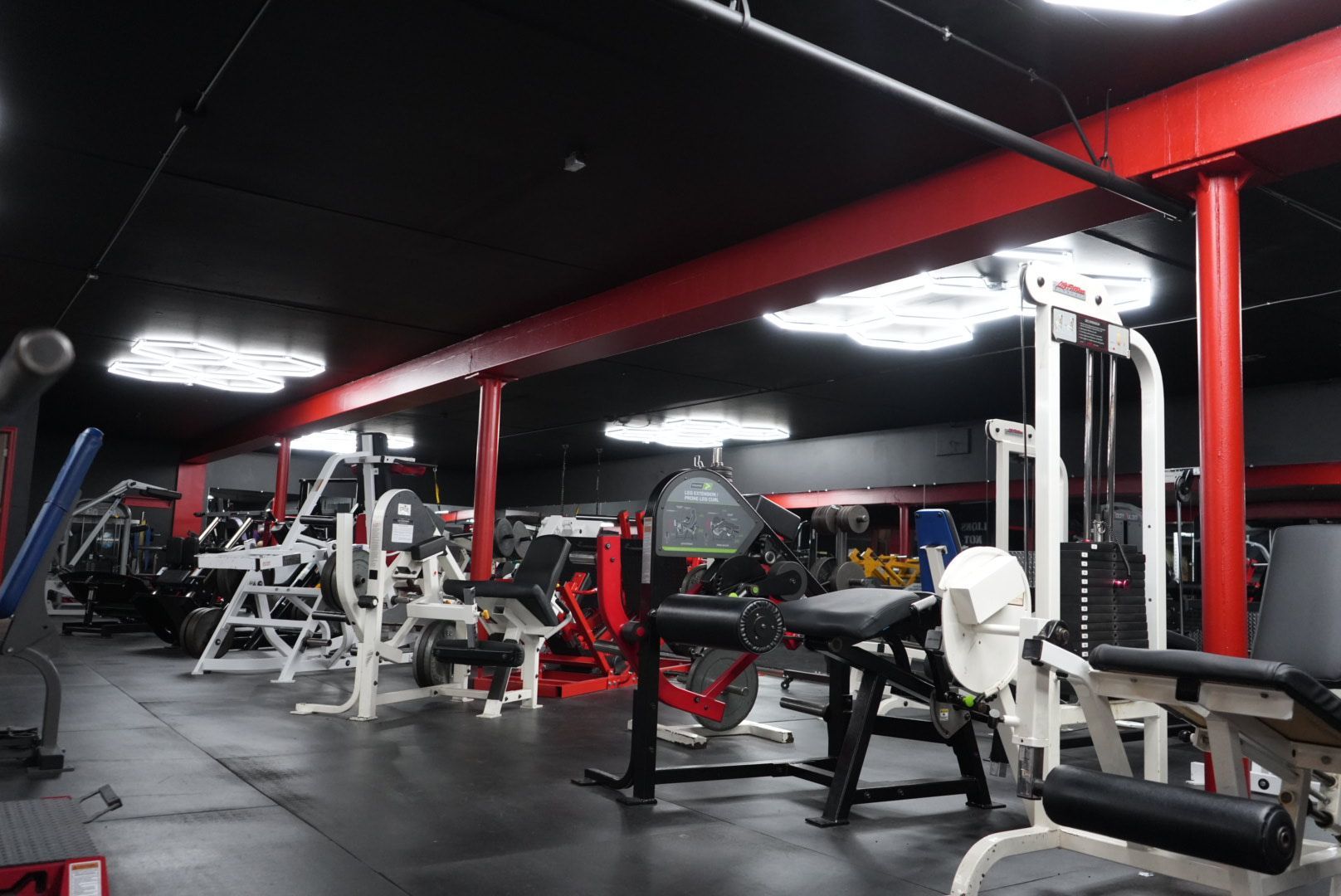 Empty gym with red and black strength machines and overhead lights