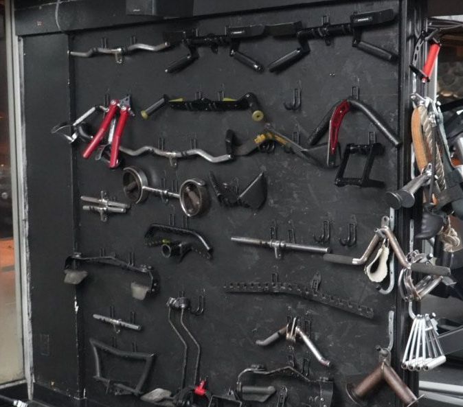 Wall of assorted hand tools and clamps arranged on a dark pegboard in a workshop