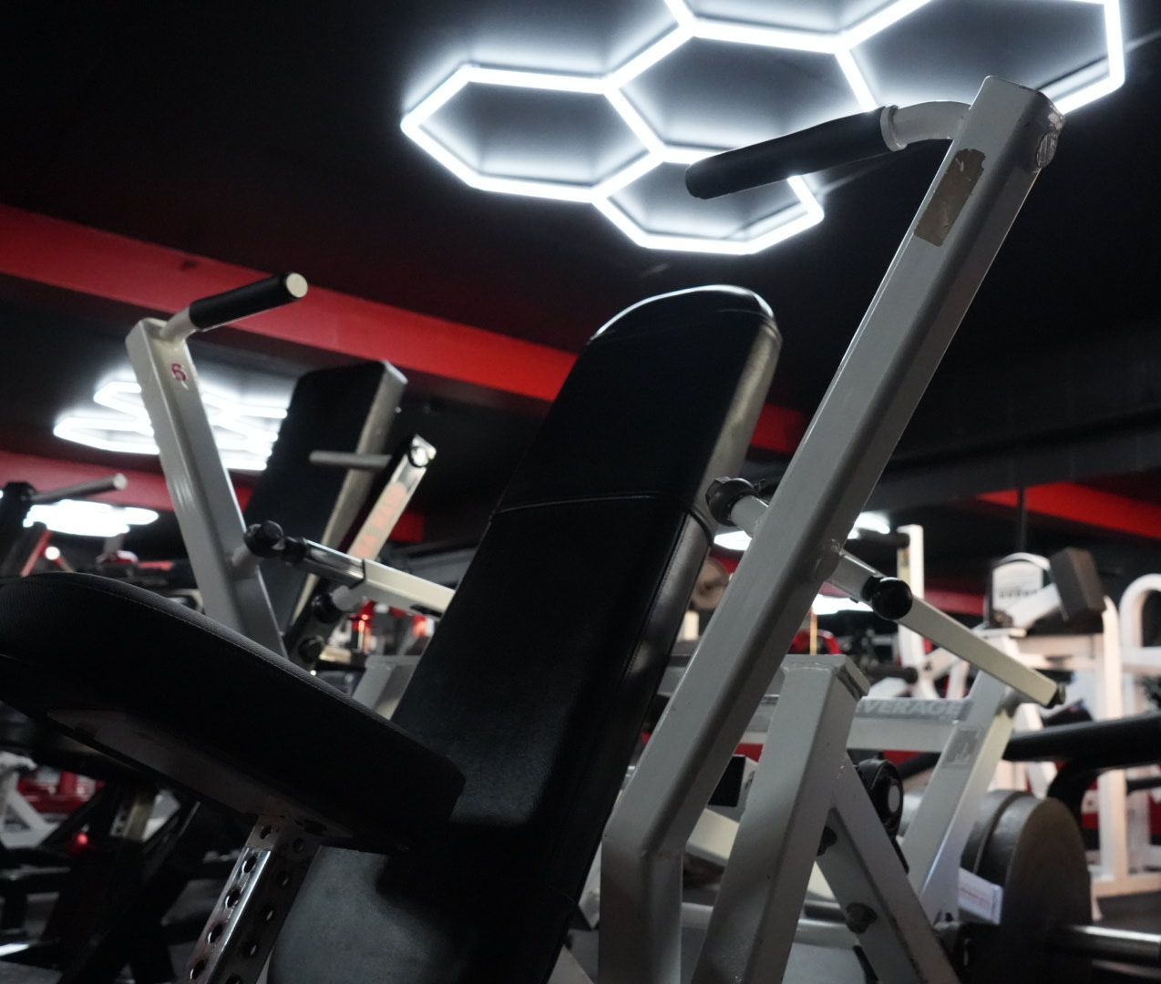Modern gym with exercise machines and bright hexagonal ceiling lights