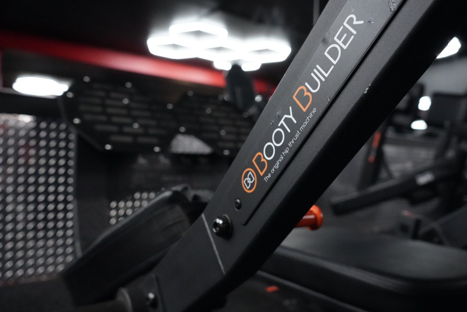 Close-up of a black gym machine frame labeled “ROBOT BUILDER” in a dimly lit fitness room