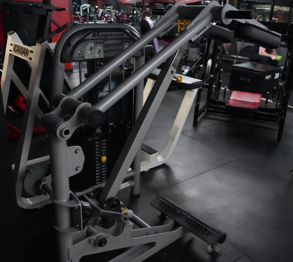 Black gym exercise machine with metal frame and handles in a fitness room