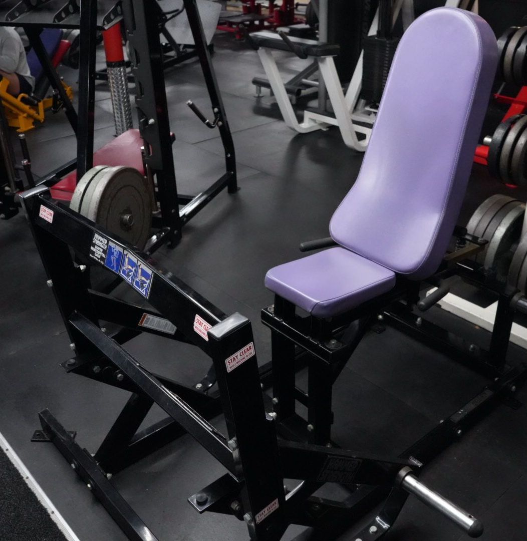 Purple padded gym machine with a seat and backrest in a weight room