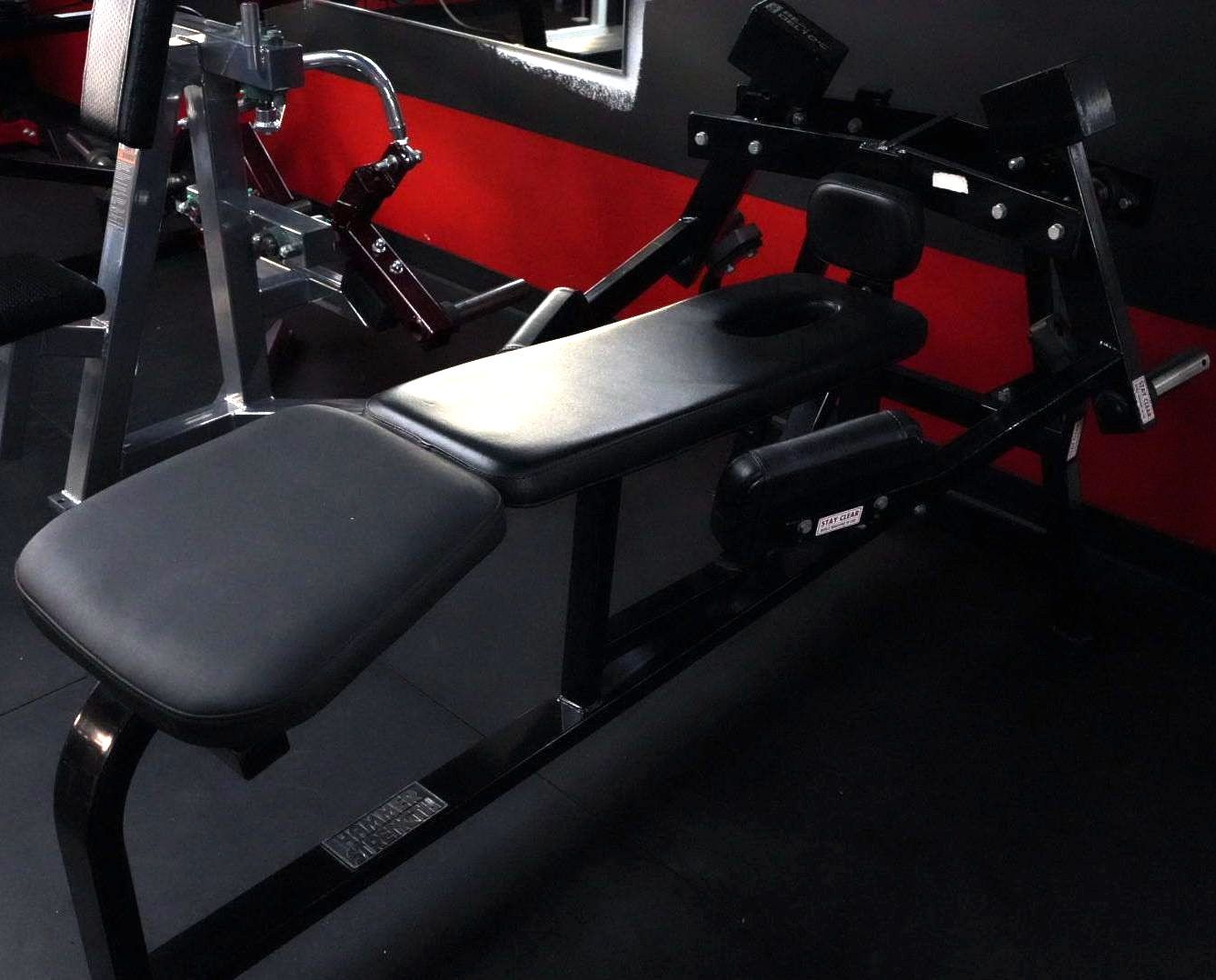 Black gym workout bench with red frame and padded seat in a dim room