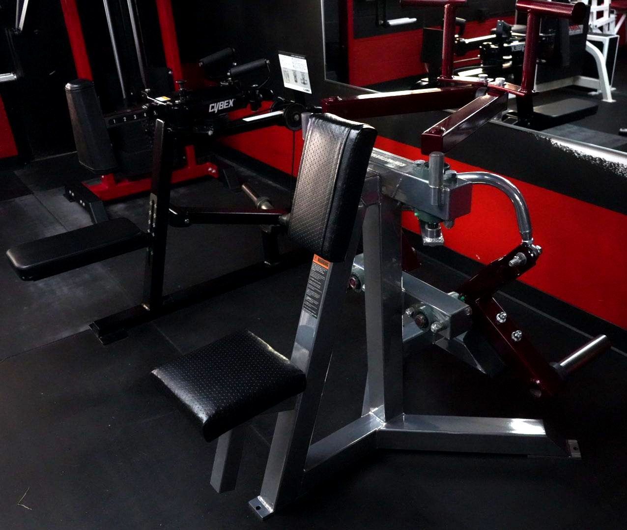 Black and red gym machine with padded seat and backrest in a fitness room