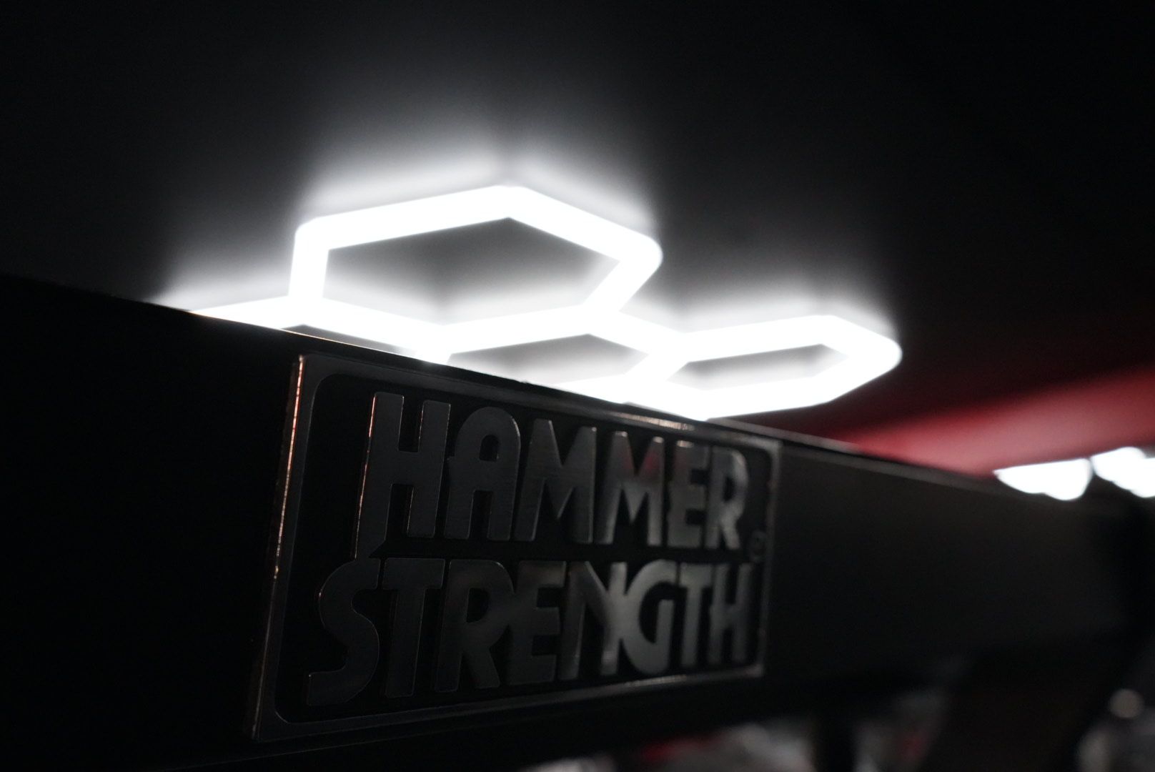 Hammer Strength logo on a gym machine, lit by bright white ceiling lights.