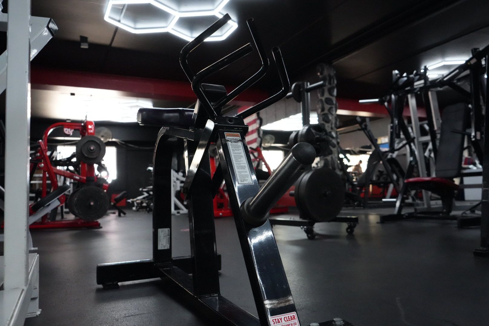 Modern gym interior with strength machines, black-and-red equipment, and geometric ceiling lights