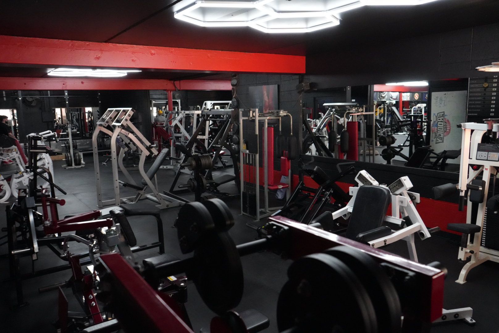 Modern gym interior with red and black equipment and mirrors