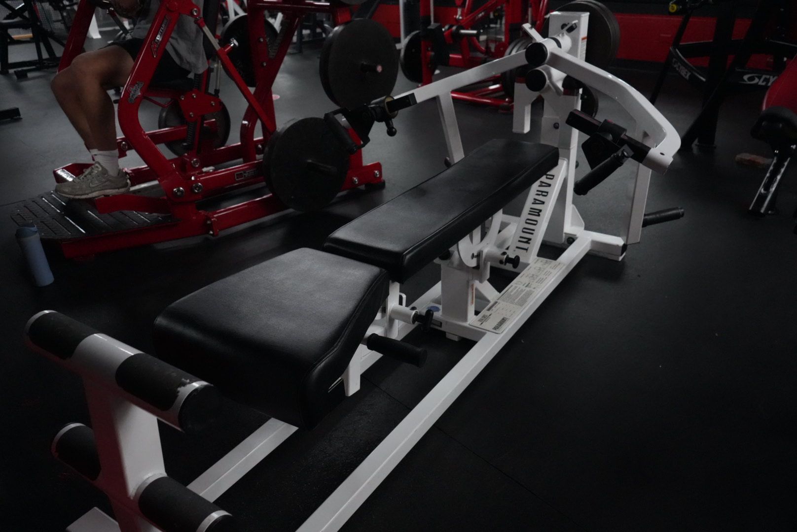 Gym with black bench press machine and red exercise equipment in the background