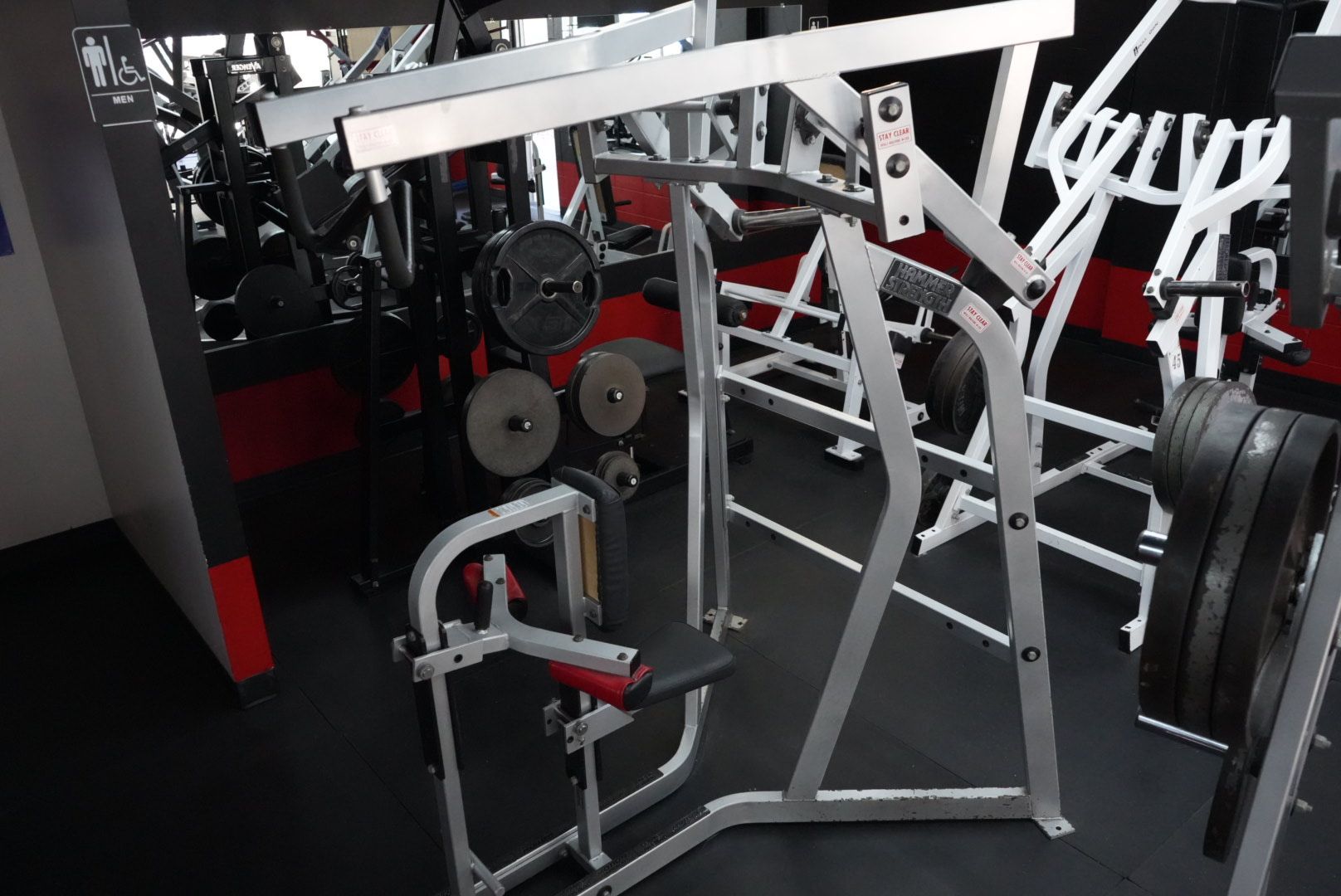 Indoor gym machine with white frame, black padding, and weight plates on the right
