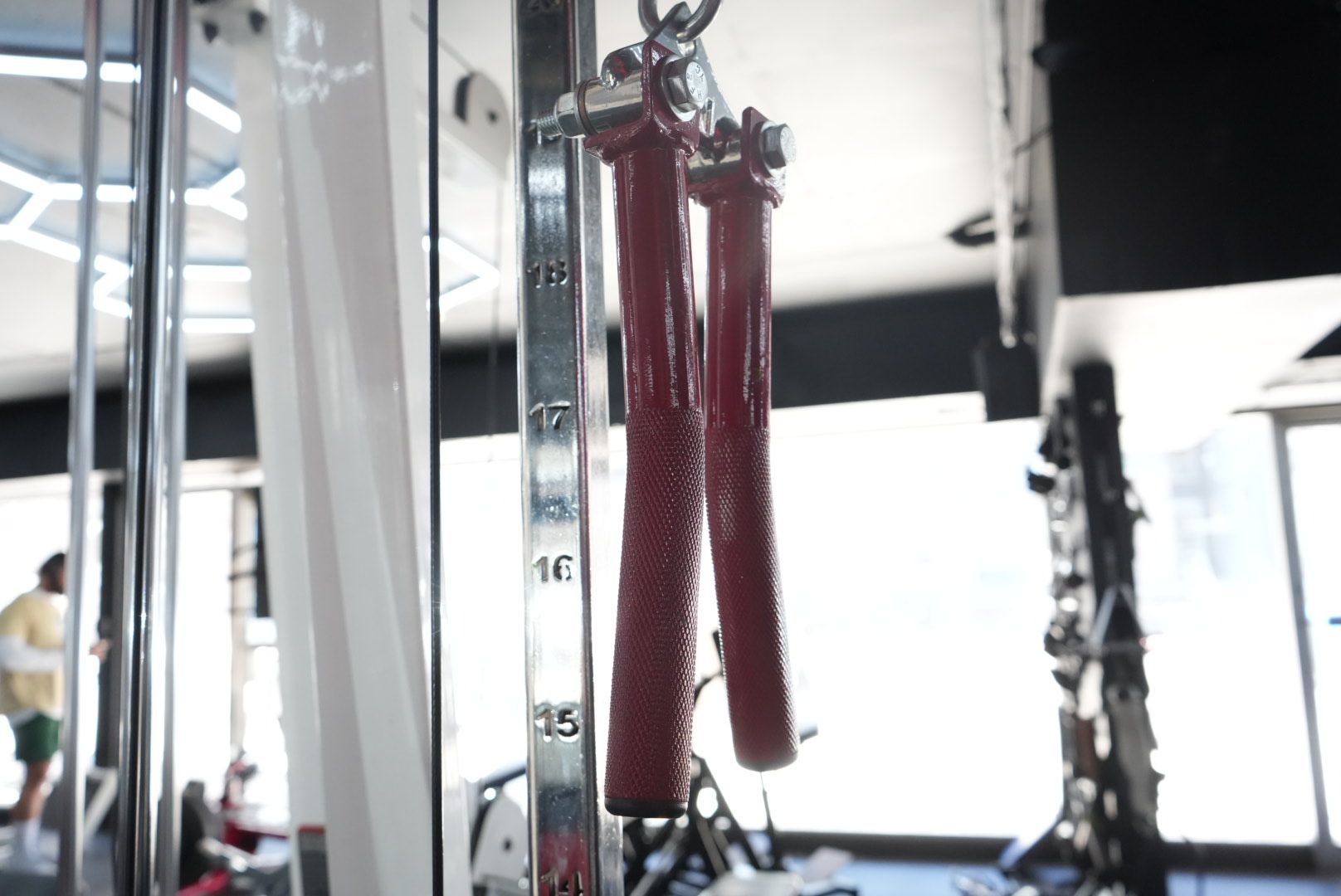 Red exercise resistance bands hanging from a gym cable machine.