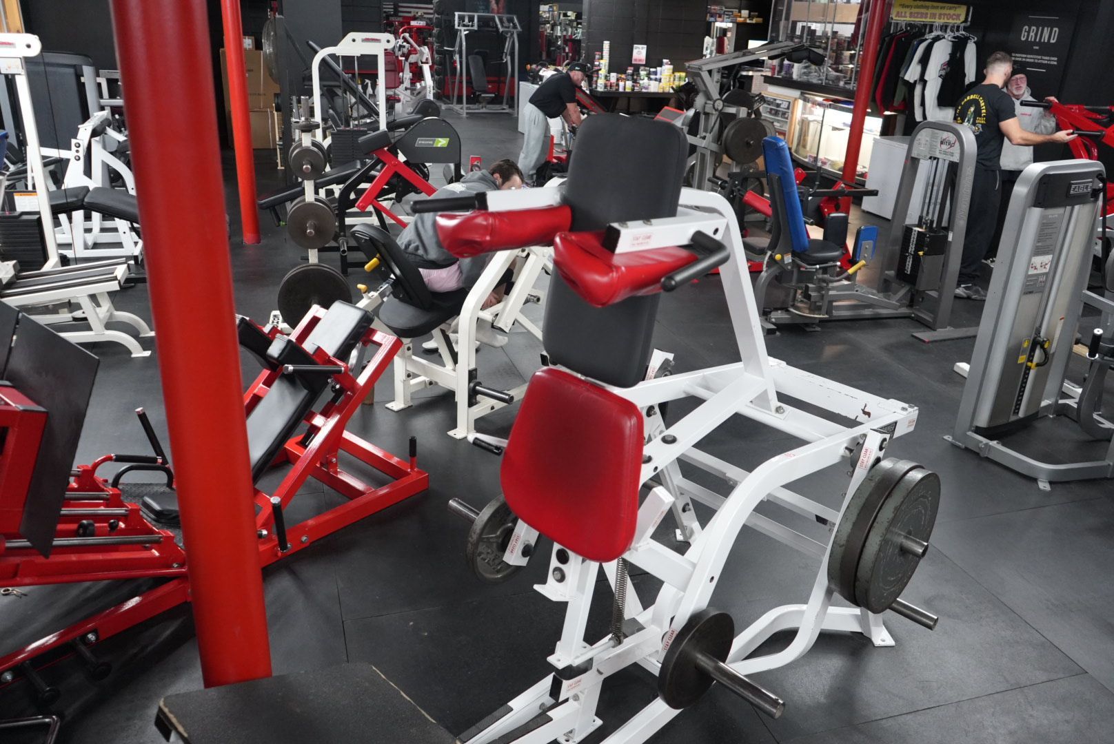 Gym interior with red and white strength machines and black rubber flooring