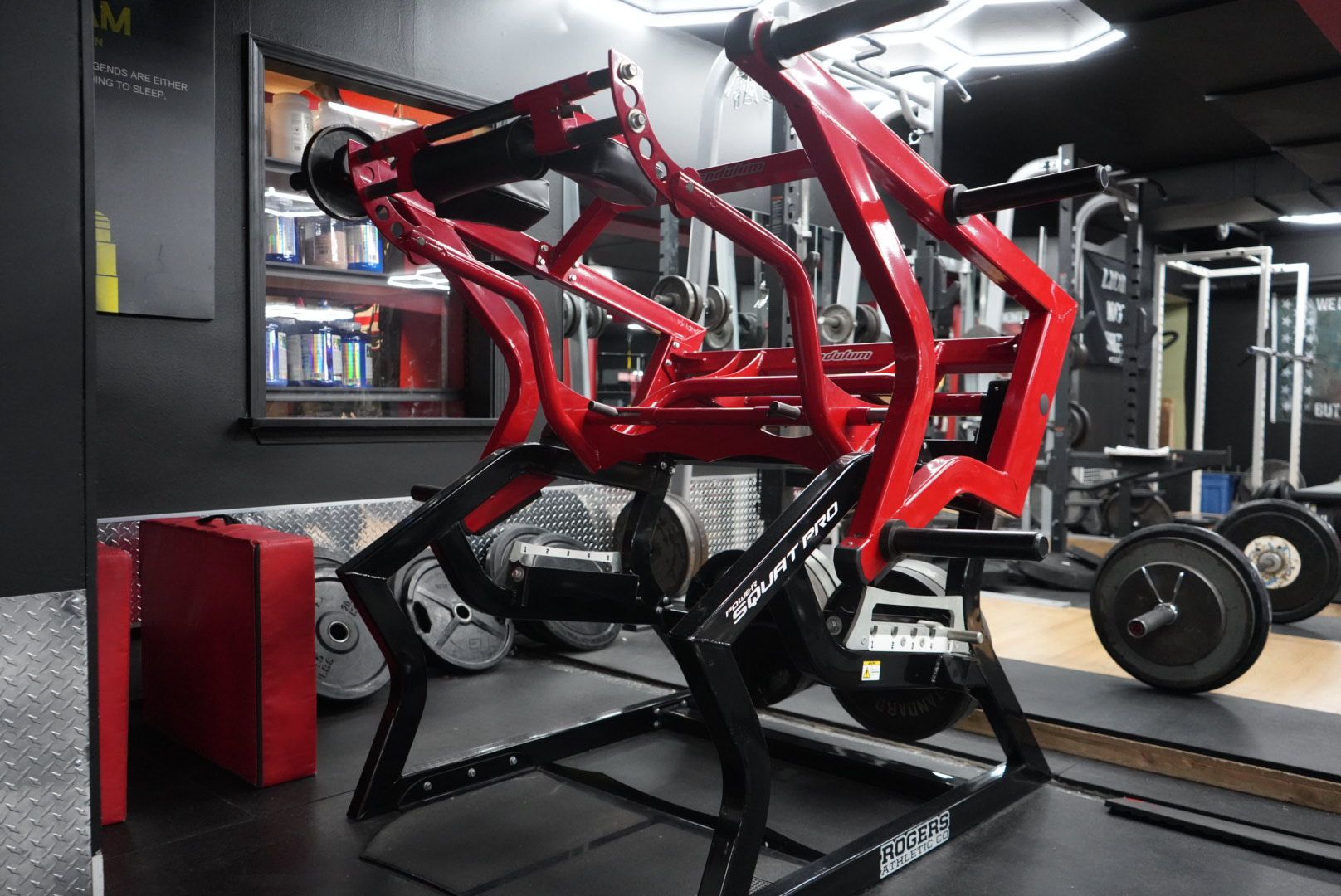 Red off-road vehicle chassis in a garage, shown on a lift with wheels nearby.