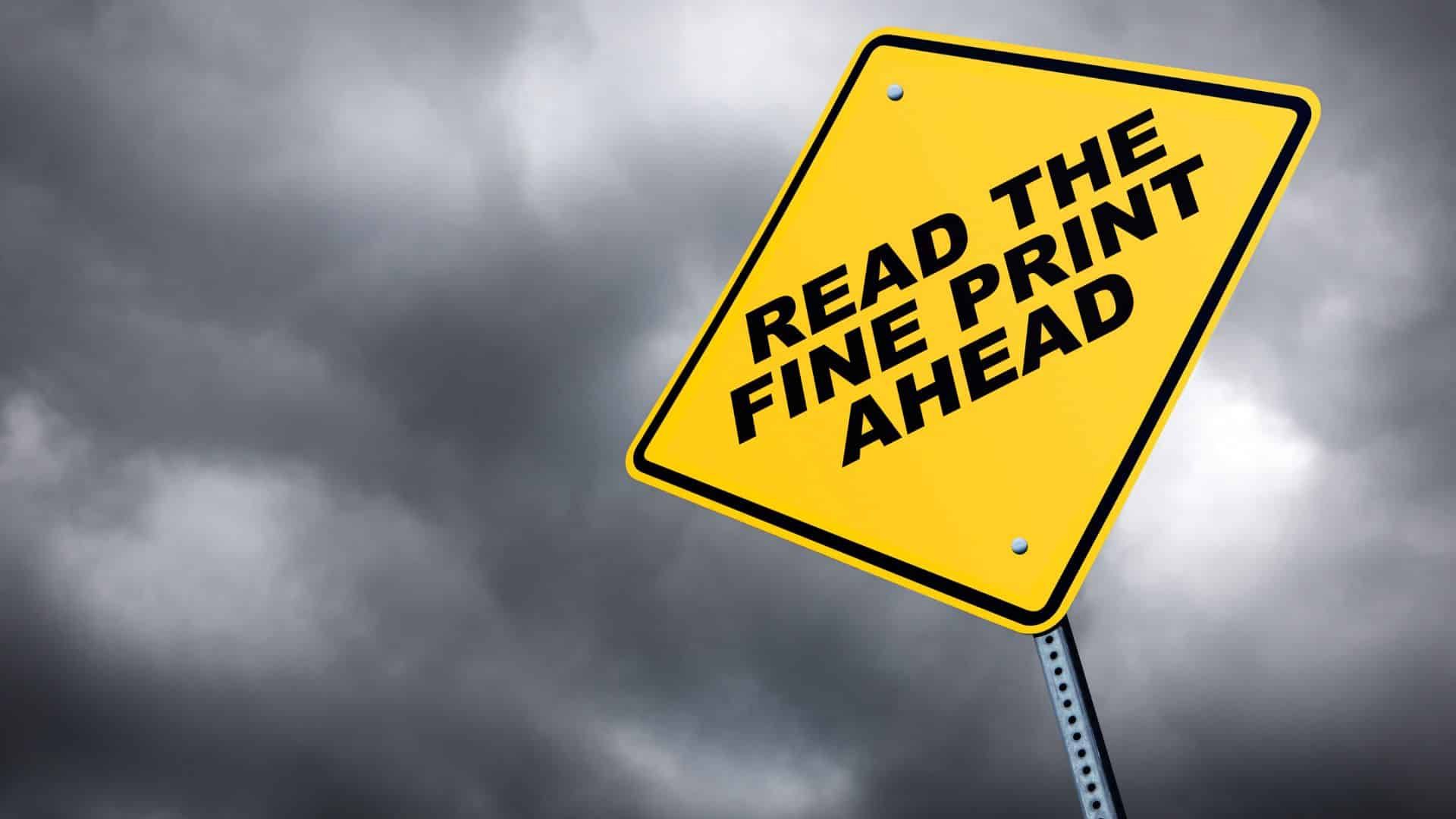 A yellow sign that says read the fine print ahead