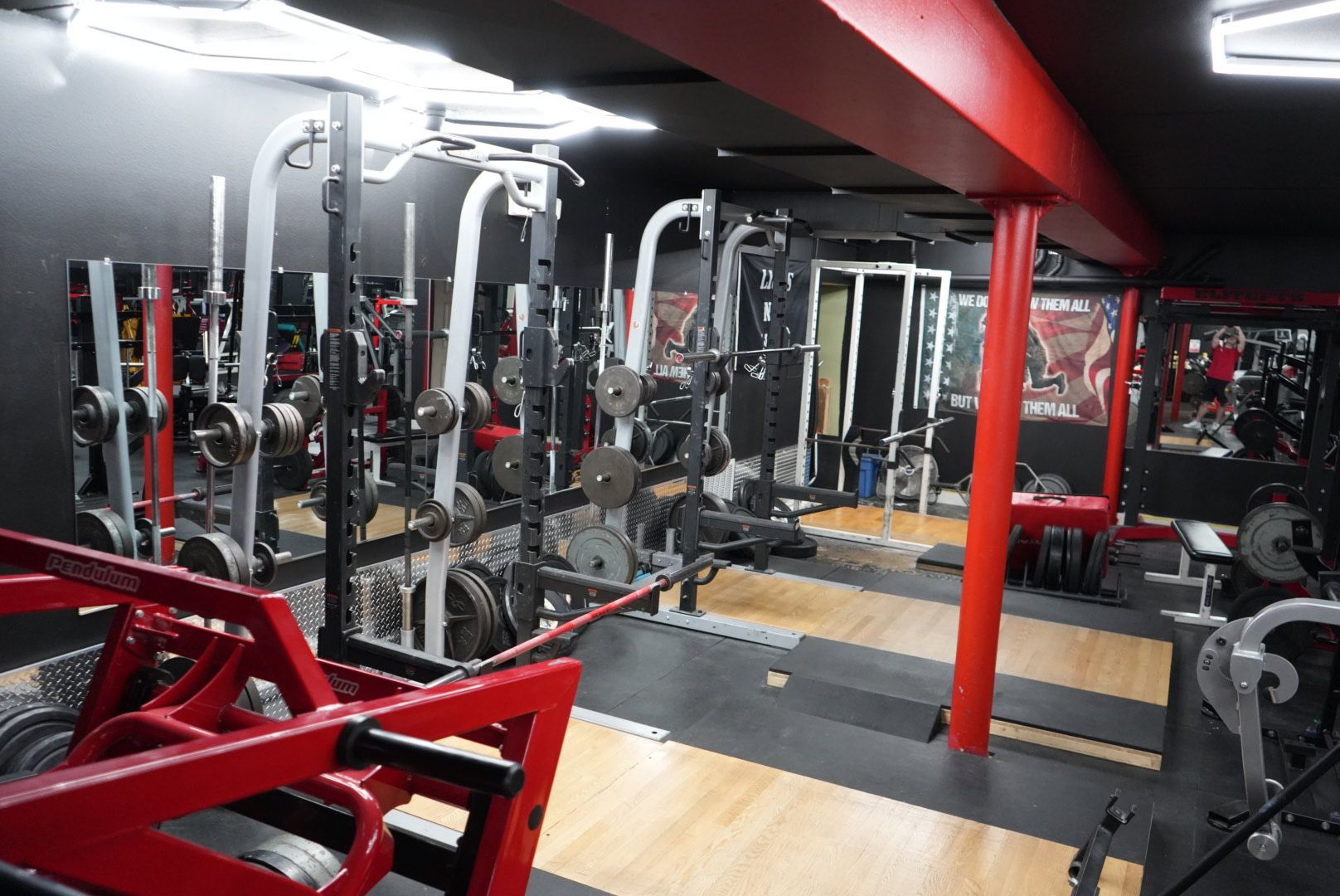 Empty gym with red and black workout machines and mirrors