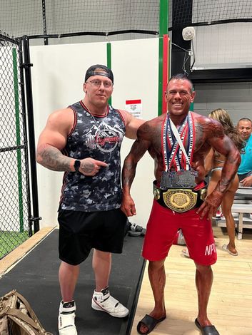 Two men are standing next to each other on a stage with medals around their necks.