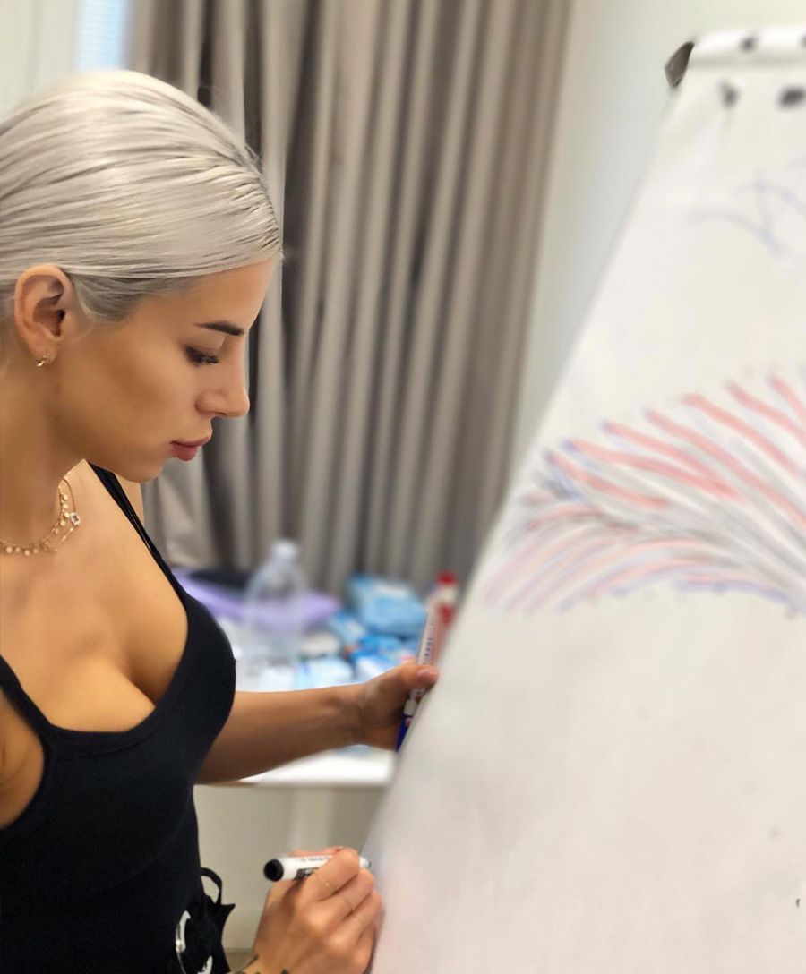 Una donna con una maglietta nera disegna su una grande lavagna bianca in uno studio.