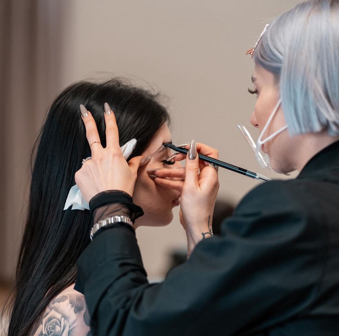Una truccatrice applica il trucco agli occhi di una cliente in una scena ravvicinata di un salone di bellezza.
