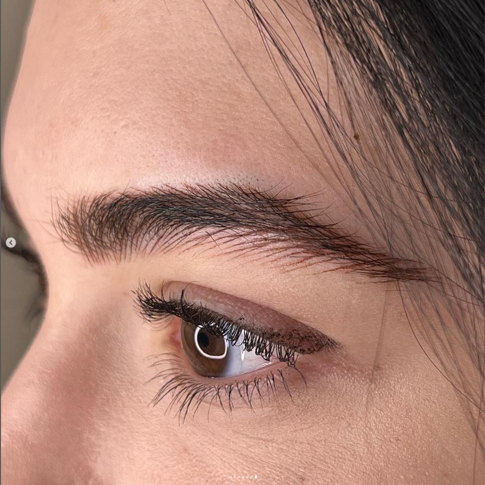 Primo piano di un occhio marrone con eyeliner scuro e sopracciglio di profilo