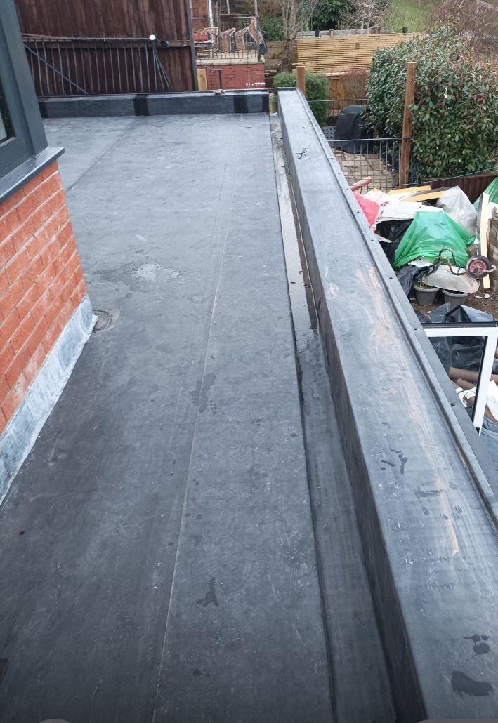 A black roof with a brick wall in the background