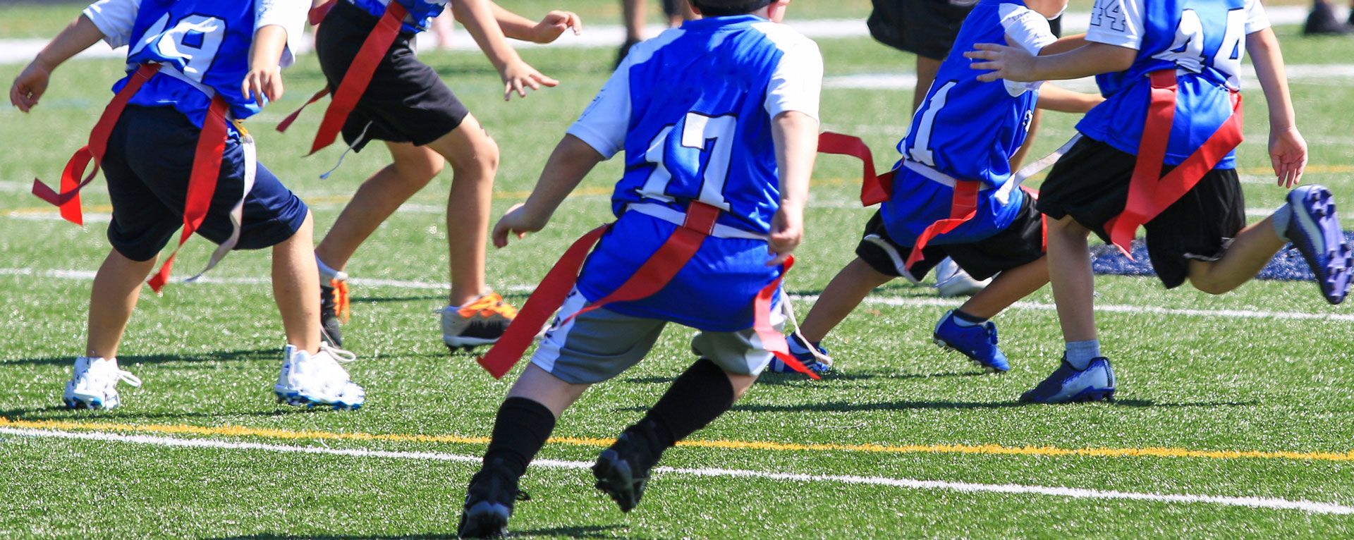Youth soccer players in blue and red jerseys running on a grassy field during a game