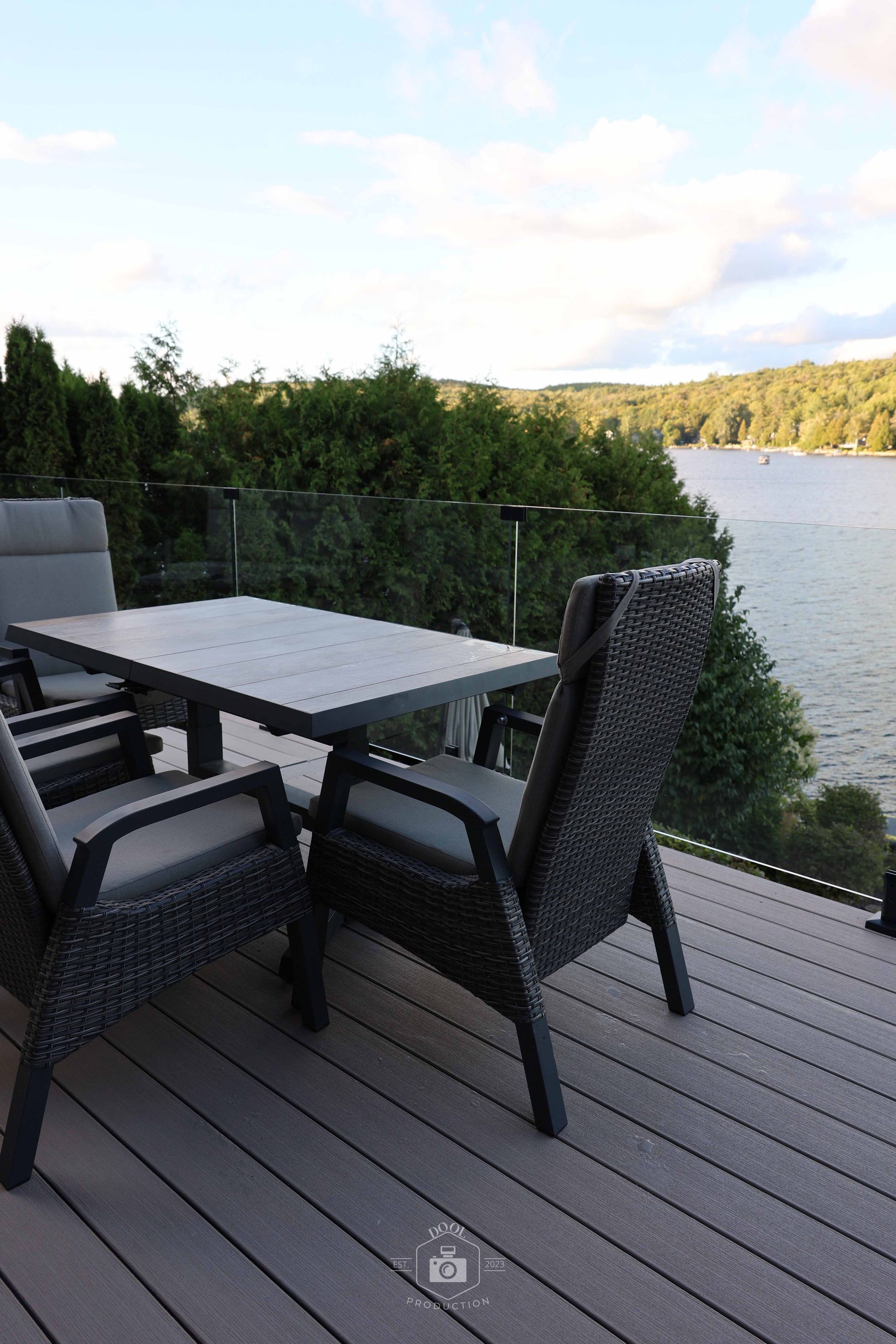 Terrasse extérieure avec table et chaises donnant sur un lac.