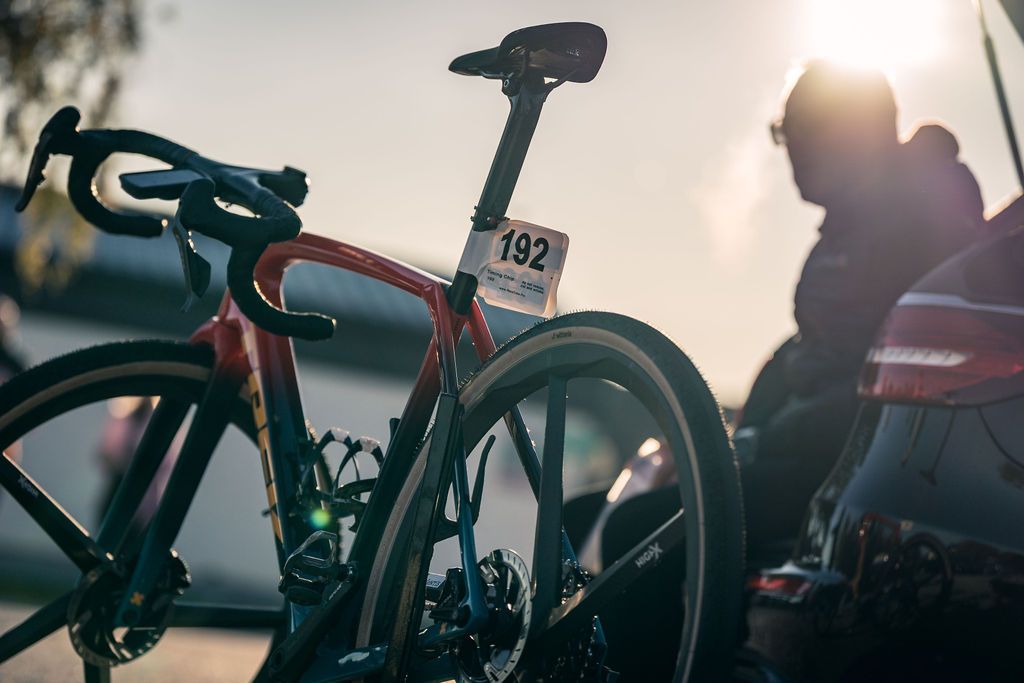 Rennrad mit der Nummer 92 im Sonnenlicht, im Hintergrund ein verschwommener Radfahrer.