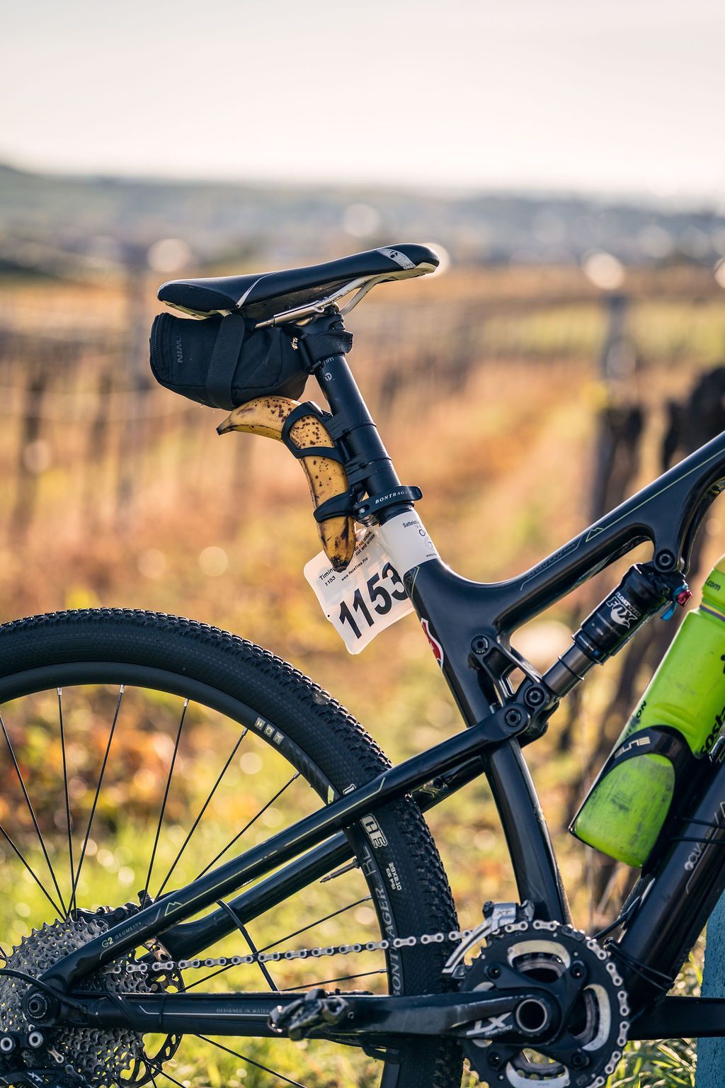 Nahaufnahme eines schwarzen Mountainbikes mit der Startnummer 1163 auf einem sonnenbeschienenen Trail