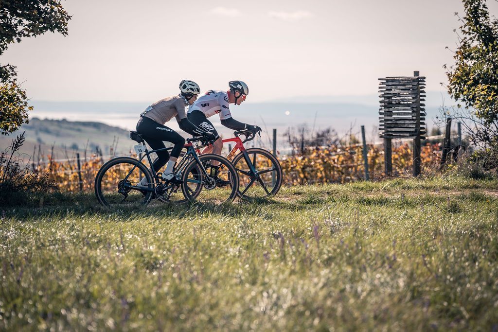 Zwei Radfahrer fahren bei Sonnenuntergang mit Mountainbikes durch ein grasbewachsenes Feld.