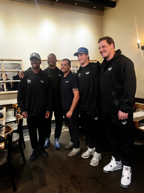 Four people in black team outfits posing together indoors in a store.