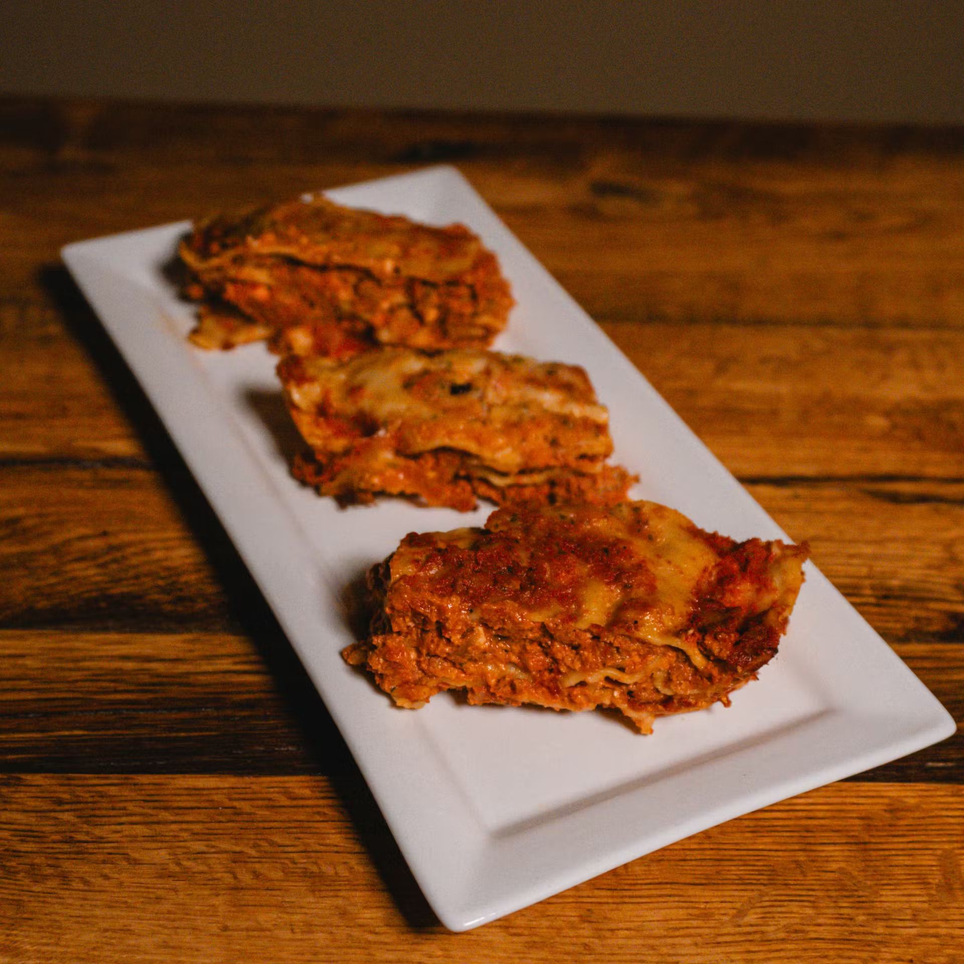 Three golden-brown fried fritters on a white rectangular plate