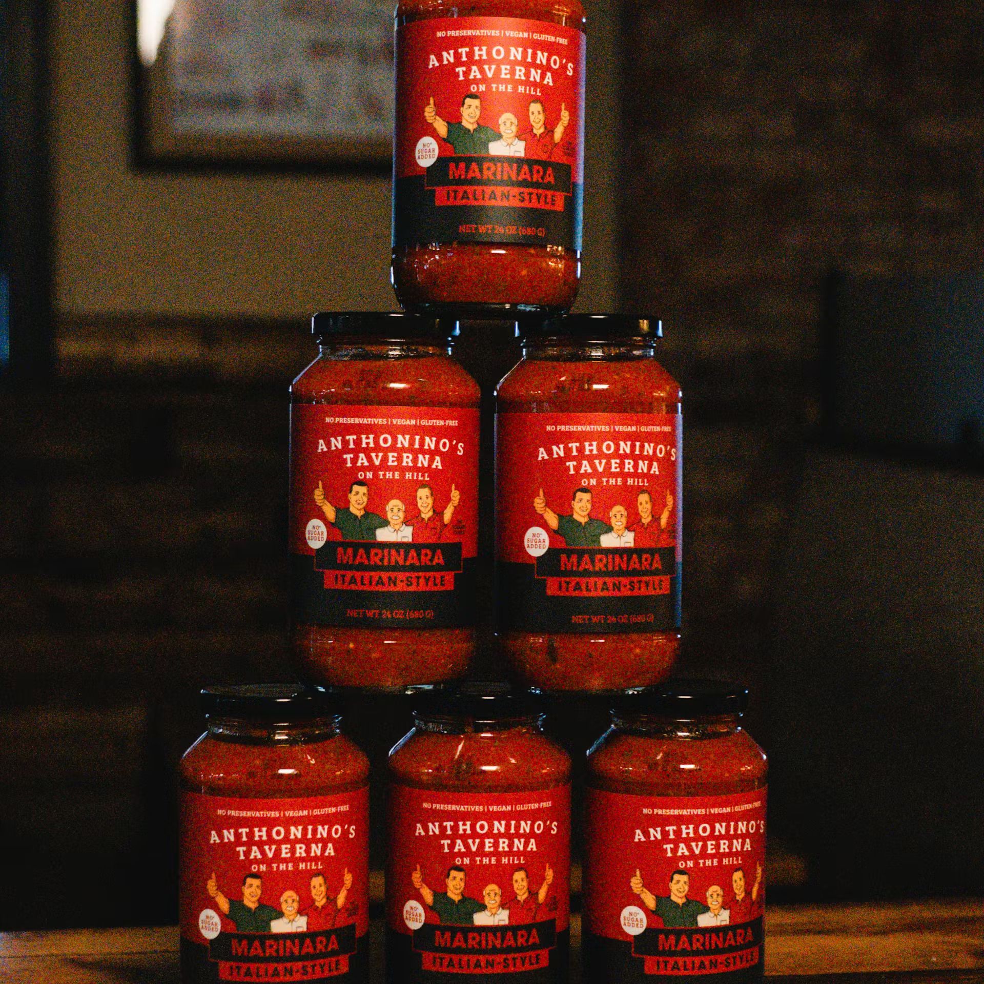 Stacked red jars of Marmite in a pyramid on a dark shelf
