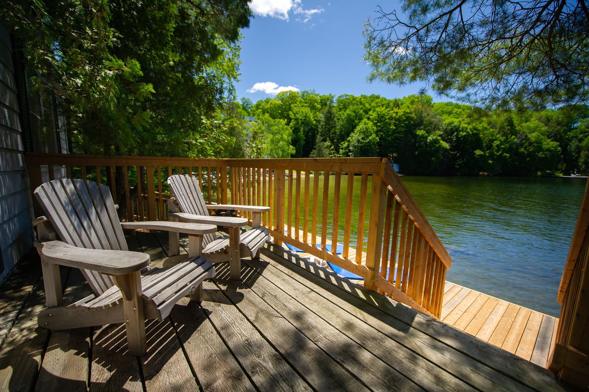 A wooden deck with chairs on it overlooking a lake