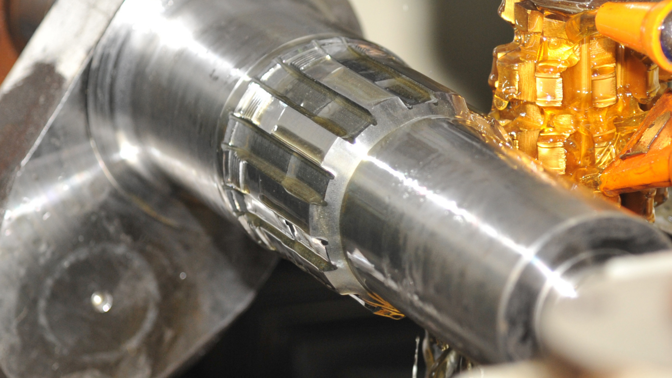 A CNC milling machine cuts into a metal workpiece held in an orange vise, surrounded by blue metal shavings.