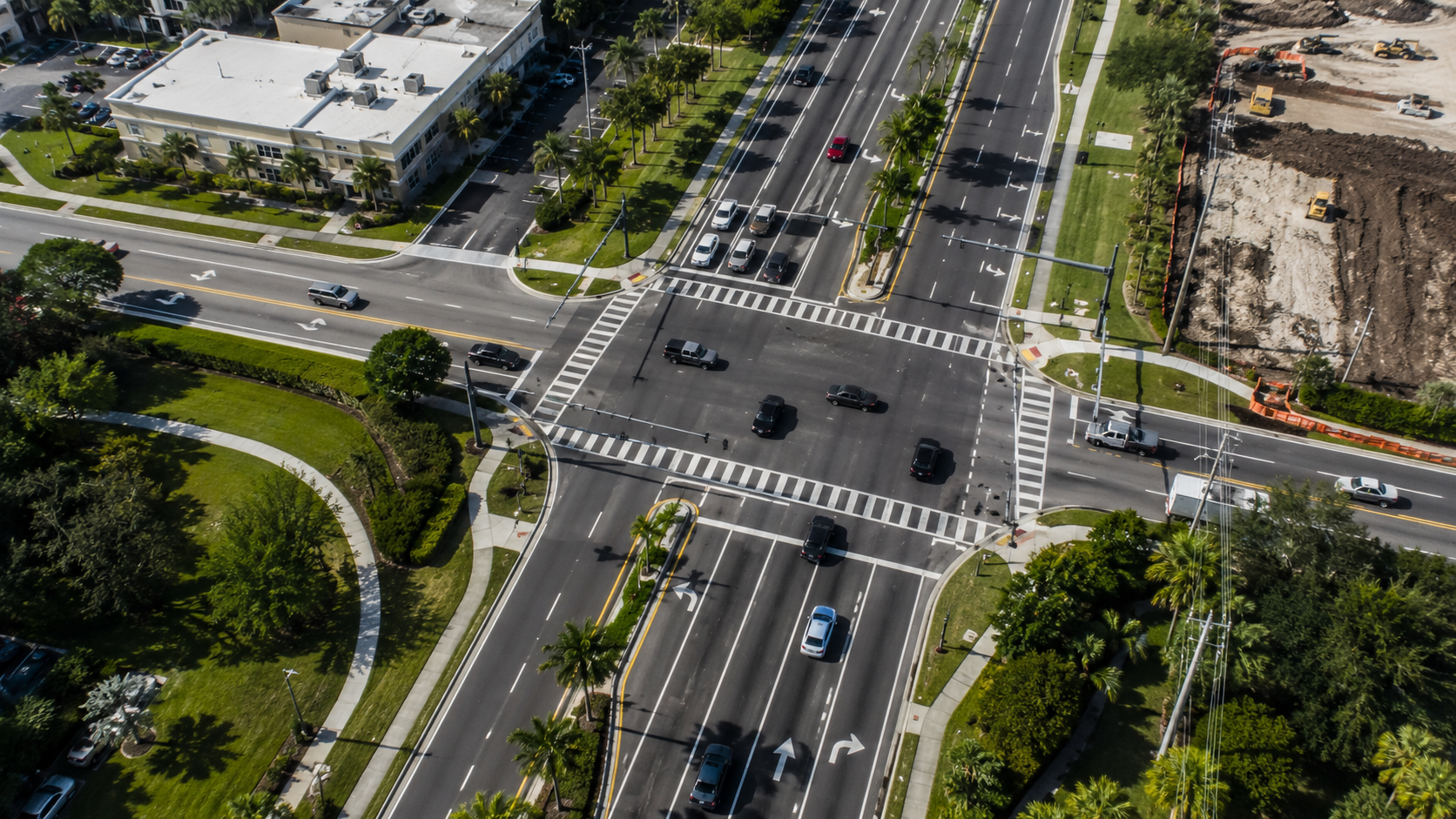 Aerial view of an intersection showing traffic controls, lane markings, vegetation, access points, a