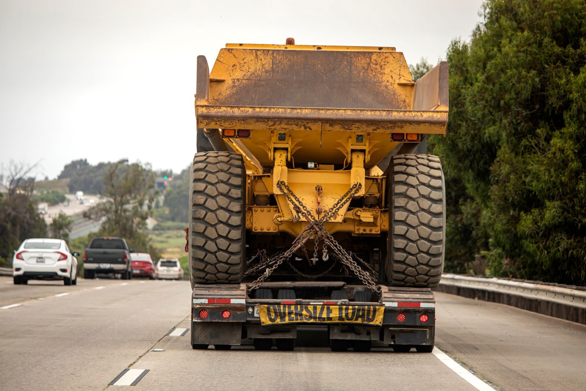 A very large haul dump truck being hauled by an 18 wheel truck down a freeway