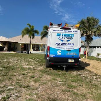 White plumbing service van parked on grass in front of a house on a sunny day