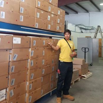 Warehouse worker standing beside stacked cardboard boxes in a storage area