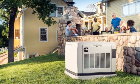 Outdoor HVAC unit beside a stone patio wall with people gathered around a backyard house