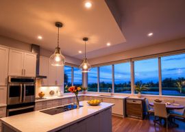 Modern kitchen and dining area with pendant lights, large windows, and a sunset view