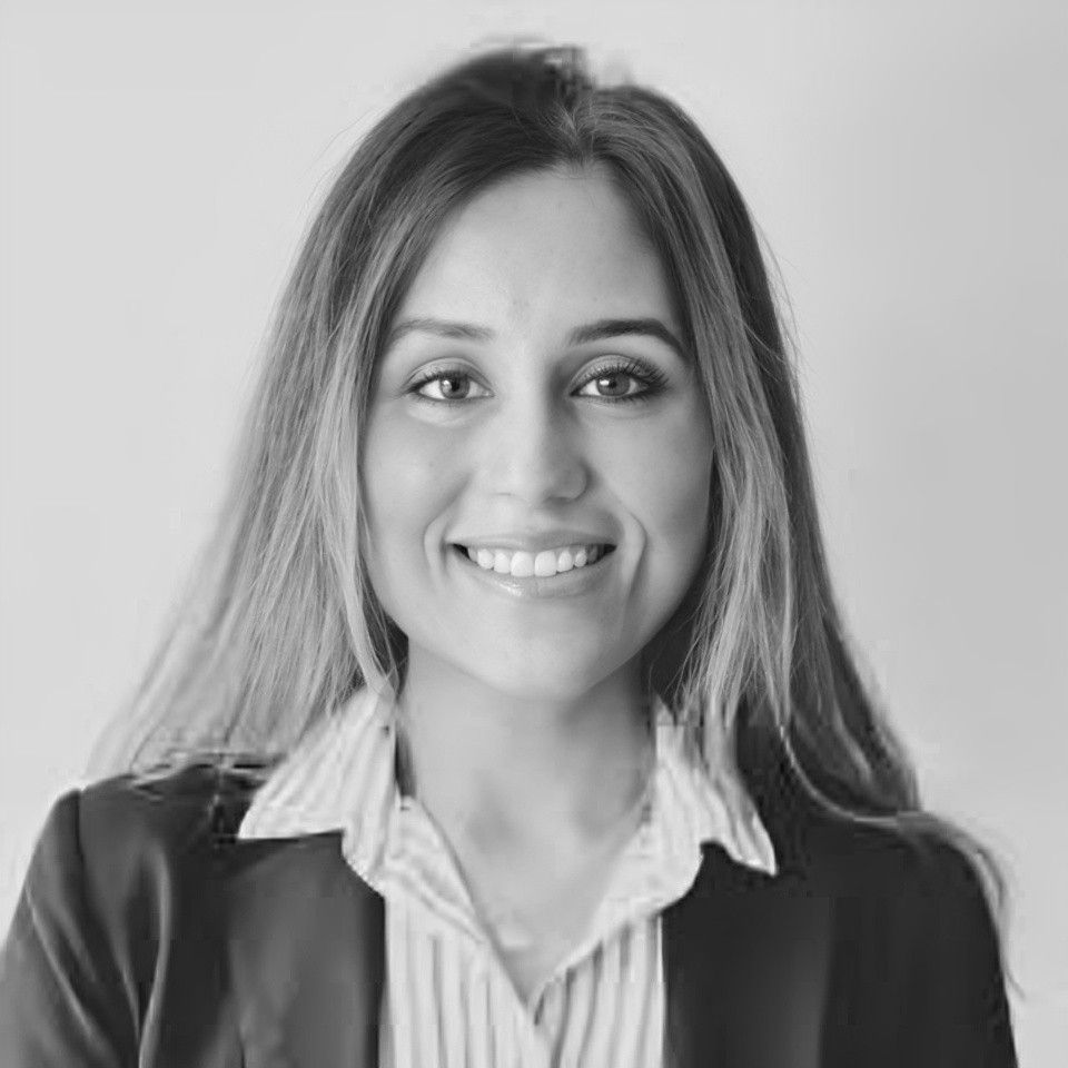 A woman in a suit and striped shirt is smiling in a black and white photo.