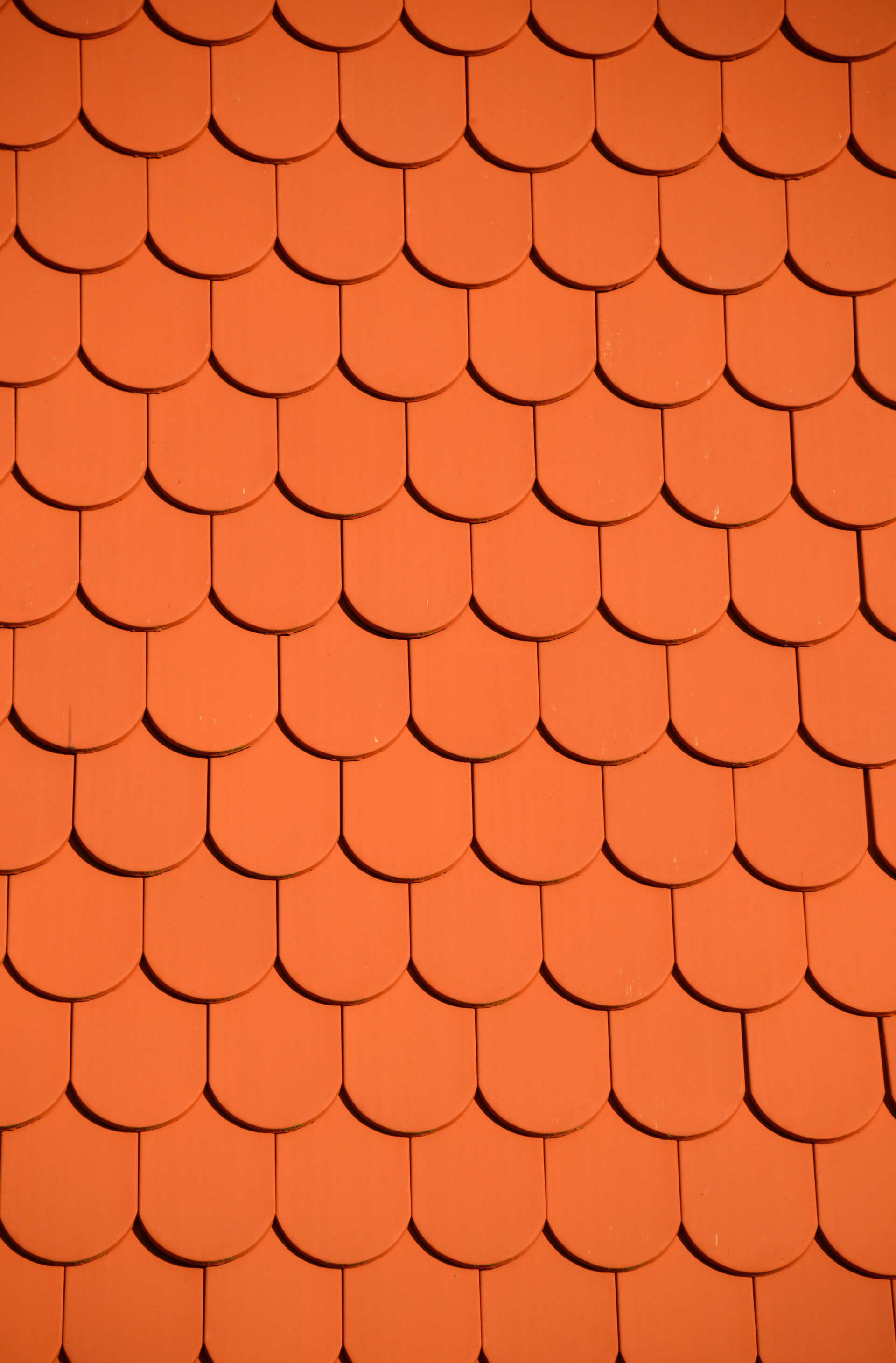 A close up of a red tile roof with a fish scale pattern