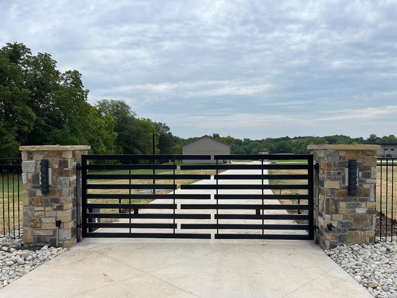 A black gate is sitting in the middle of a driveway.