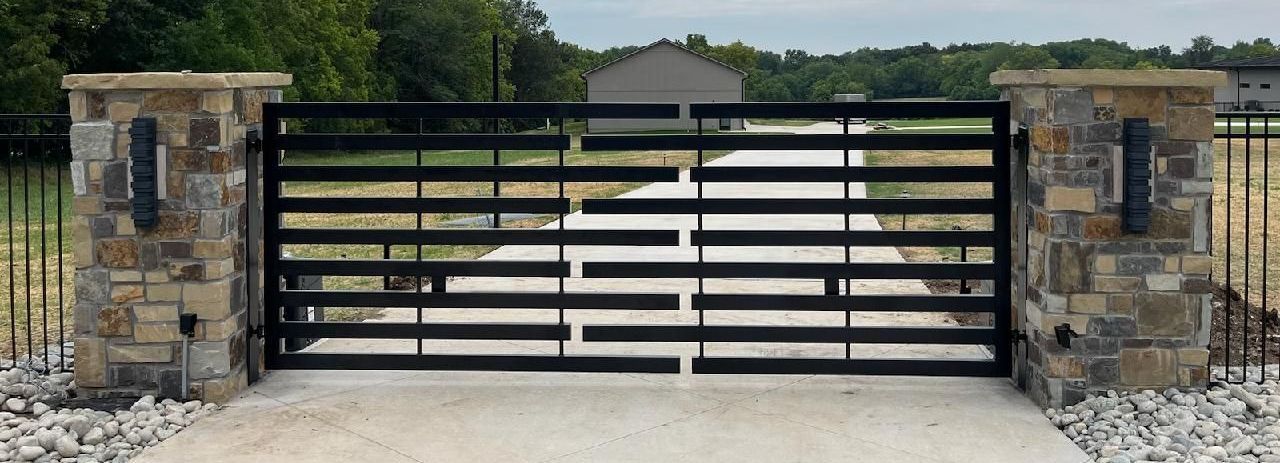 A black gate is sitting in the middle of a driveway.