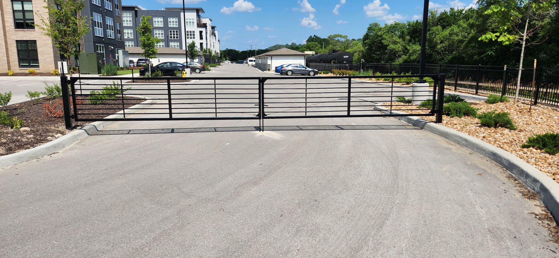 A sliding gate is blocking the entrance to a parking lot.