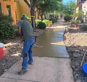 Worker smoothing fresh concrete on a sidewalk in a residential courtyard