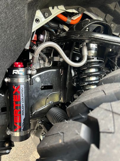 Close-up of an off-road vehicle suspension with coil spring, shock absorber, and tire tread.