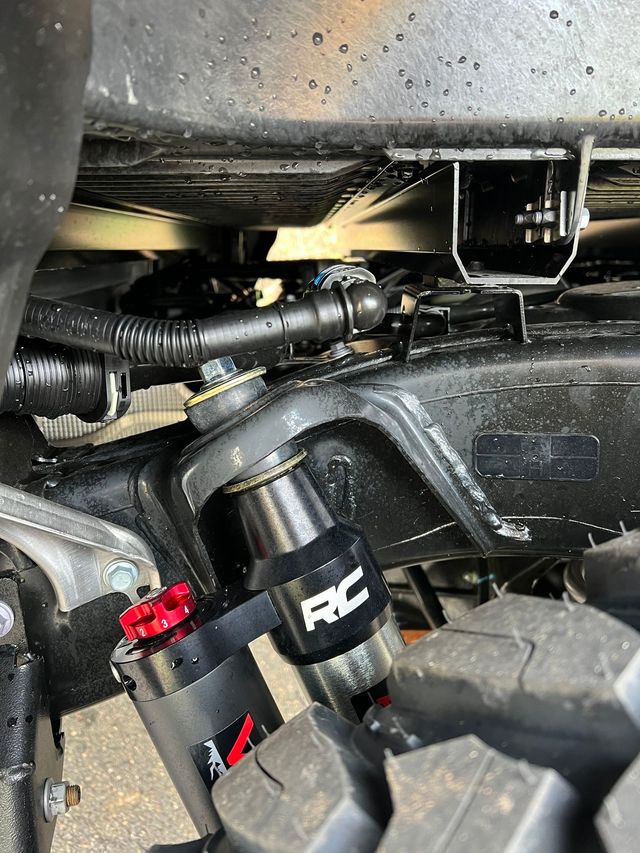 Close-up of an RC car suspension and wheel area, showing black parts and red accents under the chassis