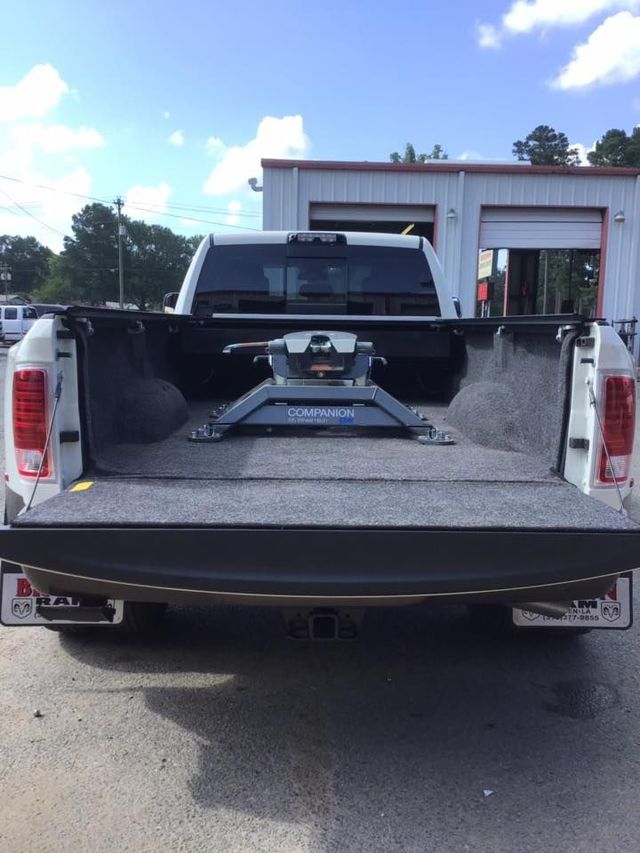Open pickup truck bed with a fifth-wheel hitch, parked outside a garage on a sunny day