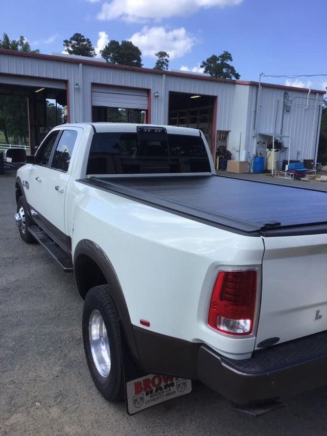 White pickup truck with black tonneau cover parked outside a garage building